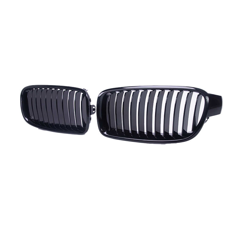 Zwei schwarze Nierengitter für ein Auto werden vor einem weißen Hintergrund dargestellt. Das glatte, glänzende Finish des M Frontgrills Schwarz für BMW 3er Serie F30/F35 (2013-2019) von RSHOP ergänzt die BMW 3er Serie perfekt, wobei jedes Gitter vertikal ausgerichtete Lamellen und ein identisches Design aufweist.